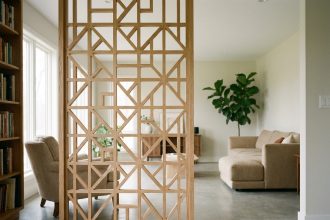 Claustra décoratif en bois clair à motif géométrique séparant un espace lecture d'un grand salon moderne